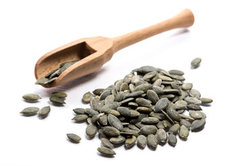 Close-up of pile of raw nuts, pumpkin seeds in a wooden spoon on white background