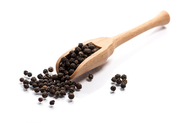 Close-up of pile of Black pepper seeds spice in a wooden spoon on white background