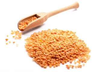 Close-up of pile of red lentils in a wooden spoon on white background
