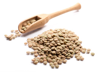 Close-up of pile of brown lentils in a wooden spoon on white background