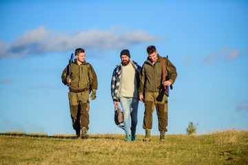 Brutal hobby. Group men hunters or gamekeepers nature background blue sky. Men carry hunting...