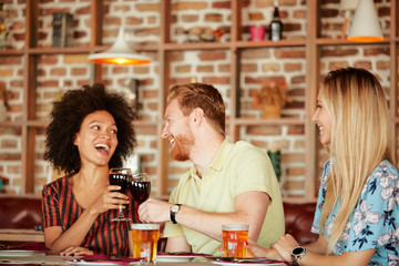 Group of friends having dinner at restaurant. Friends cheering and drinking alcohol.