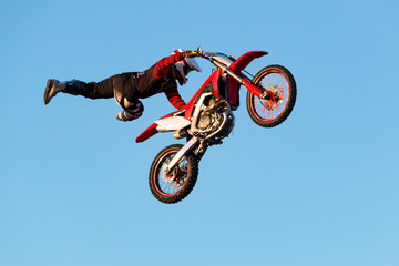 Freestyle motocross biker performs the trick in jump at fmx competitions