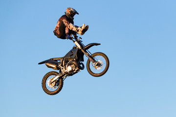 Freestyle motocross rider performs the trick in jump at fmx competitions