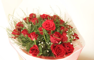A big bouquet of re roses with decoration in a wrapping paper with a white background (horizontal)