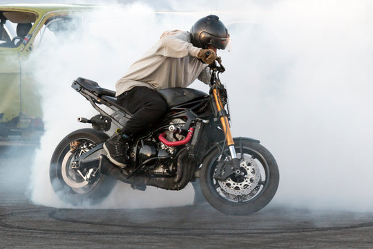 Biker burning tires and creating smoke on motorcycle in motion
