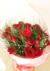 A big bouquet of re roses with decoration in a wrapping paper with a white background (vertical)