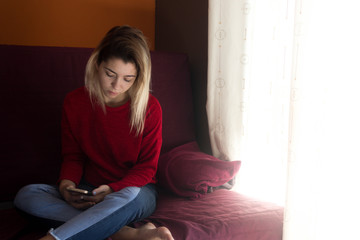 Fototapeta premium pretty young girl at home with mobile phone