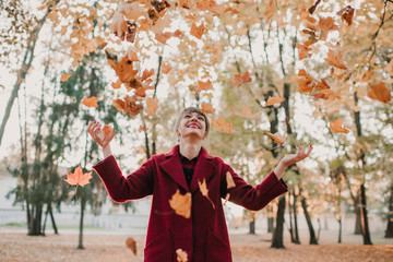 Cheerful woman throwing leaves up
