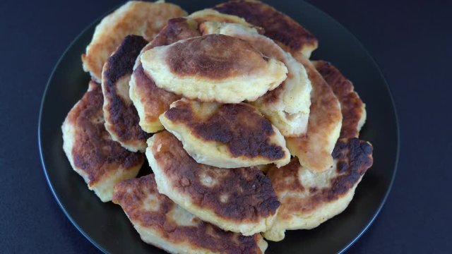 Potato cakes, ukrainian name potato zrazy, stuffed mushrooms or meat or cheese with herbs cream are fried in vegetable oil on black background, close up, rotates. Traditional Ukrainian cuisine