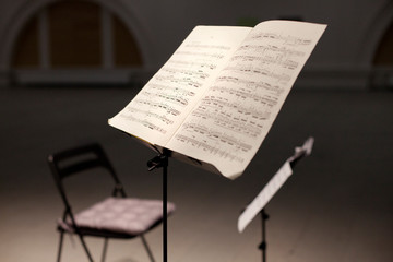 Fototapeta na wymiar Music stand with notes and chair on the stage