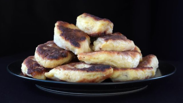 Potato cakes, ukrainian name potato zrazy, stuffed mushrooms or meat or cheese with herbs cream are fried in vegetable oil on black background, close up, rotates. Traditional Ukrainian cuisine
