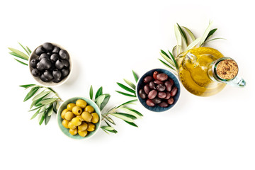 Overhead photo of various olives in bowls and a cruet of olive oil, shot from the top on a white background with copy space