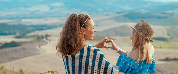 happy mother and daughter travellers showing heart shaped hands