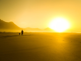 Silhouette of mother with her little child on a summer day in Fuerteventura.