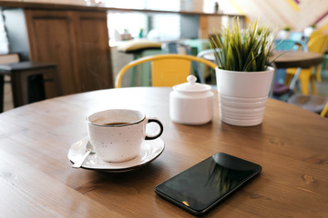 Coffee drink on wooden table with blur cafeteria as background.