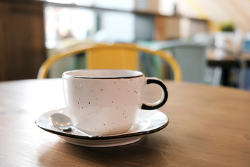 Coffee drink on wooden table with blur cafeteria as background.