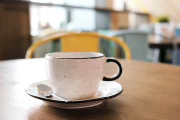 Coffee drink on wooden table with blur cafeteria as background.