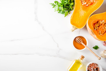 Halves of raw pumpkin or butternut squash, with olive oil, spices and ingredients for cooking 