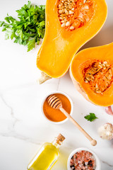 Halves of raw pumpkin or butternut squash, with olive oil, spices and ingredients for cooking 