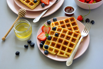 Belgian waffles with strawberries and honey on gray background. Healthy breakfast concept