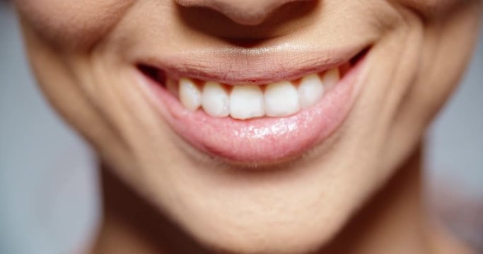 woman with pink lipstick on lips and perfectly white teeth beautifully smiling - extreme closeup 4k