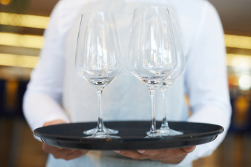 Close-up of waiter serves empty wineglasses at the restaurant