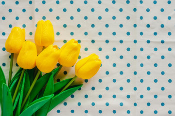 Artificial yellow tulips on blue polka dot fabric or tablecloth for nature and springtime concept