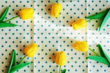 Artificial yellow tulips on blue polka dot fabric or tablecloth with sun light in the morning for nature and springtime concept