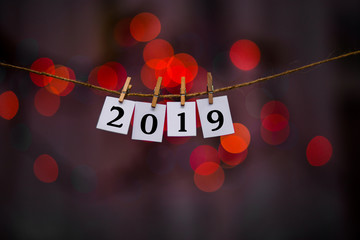 Happy new year 2019 text on papers with clothespins with garland bokeh on background. Year of pig. Holidays, winter and celebration concept