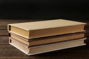 A stack of books on a brown wooden table and on a black background. Old books. Education. school. study