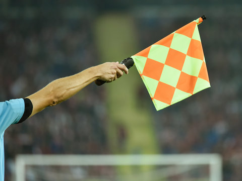Fototapeta Raised hand with flag of assistant soccer referee