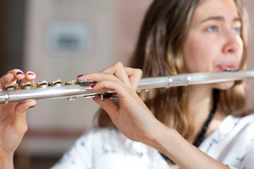 Girl plays on flute. Flute in hands of girl during the concert. Professional musician playing on...