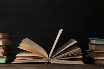 Books and unfolded book on a brown wooden table and on a black background. Old books. Education. school. study