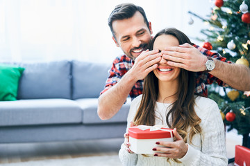 Man covering girlfriend's eyes and surprising her with christmas present
