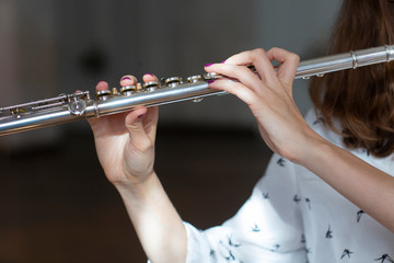 Girl plays on flute. Flute in hands of girl during the concert. Professional musician playing on...