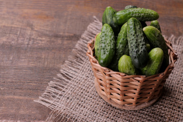 Fresh green cucumbers in a basket and slices of cucumbers on a brown wooden table. vegetables