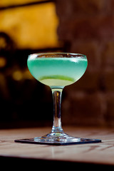 green and blue with lime alcohol cocktail in the glass on the table in bar