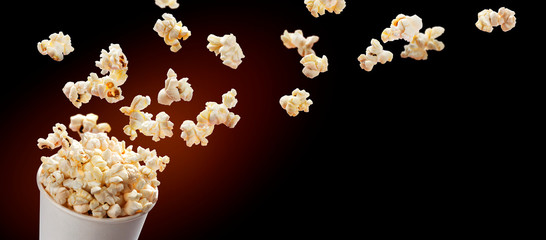 Popcorn flying out of cardboard box. Isolated on black background