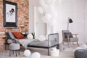 Balloons in industrial stylish bedroom with grey accents and map in black frame, real photo with...