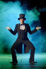 young actor in a tuxedo and hat fooling around on stage