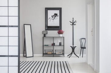 Map in black frame on the grey wall of corridor with mirror, shelf, hanger and hair, real photo