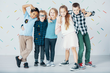 Multicultural group of children against colorful wallpaper. Young friends in the school