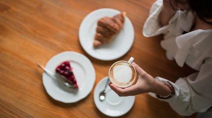 Croissant with cake with berries, chocolate spread and with cup of coffee on a marble texture background