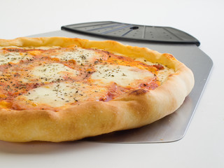 Detalle frontal de una pizza 4 quesos y utensilio para servirla