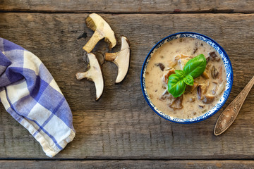 Forest mushroom soup with sour cream. Autumn food on wooden background.