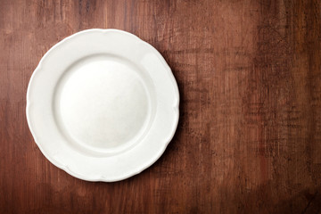White plate, shot from the top on a dark rustic wooden background with copy space