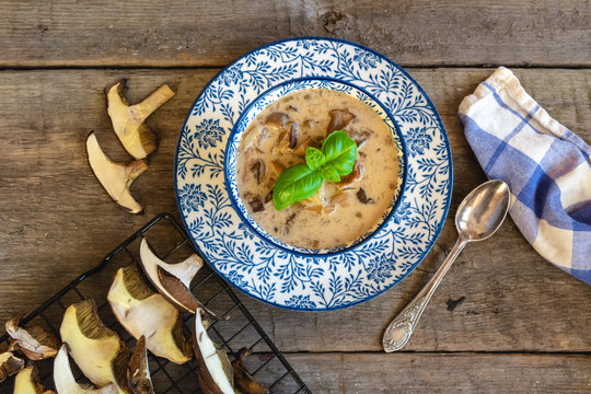 Forest mushroom soup with sour cream. Autumn food on wooden background.