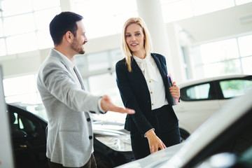 Handsome salesman at car dealership selling vehichles