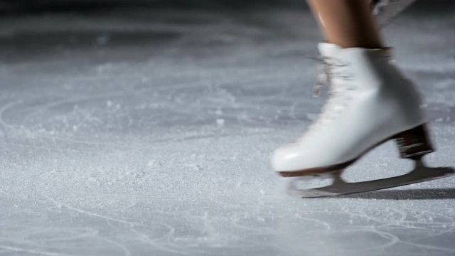 The girl slightly lifts her leg up when she spins on the ice. We can see her cute white skates.